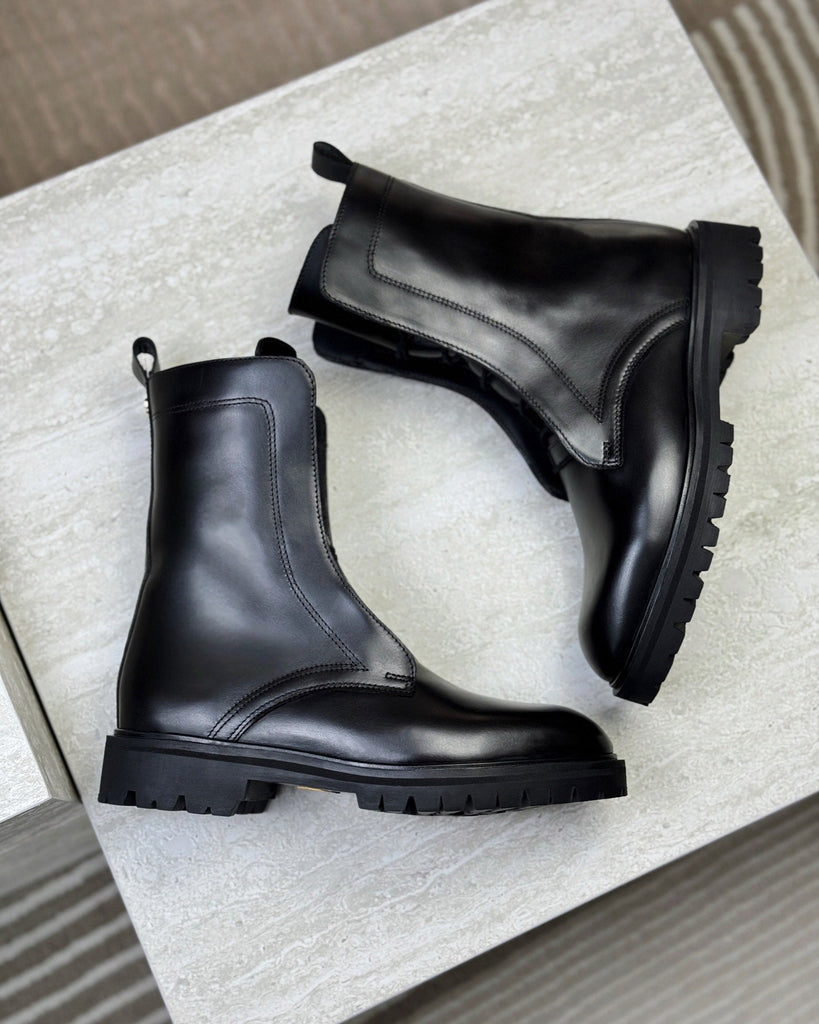 Pair of black leather boots on a light gray surface