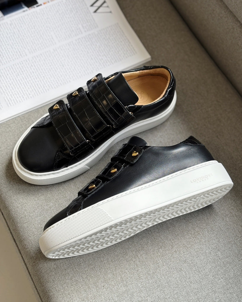 Black sneakers with white soles on a gray surface